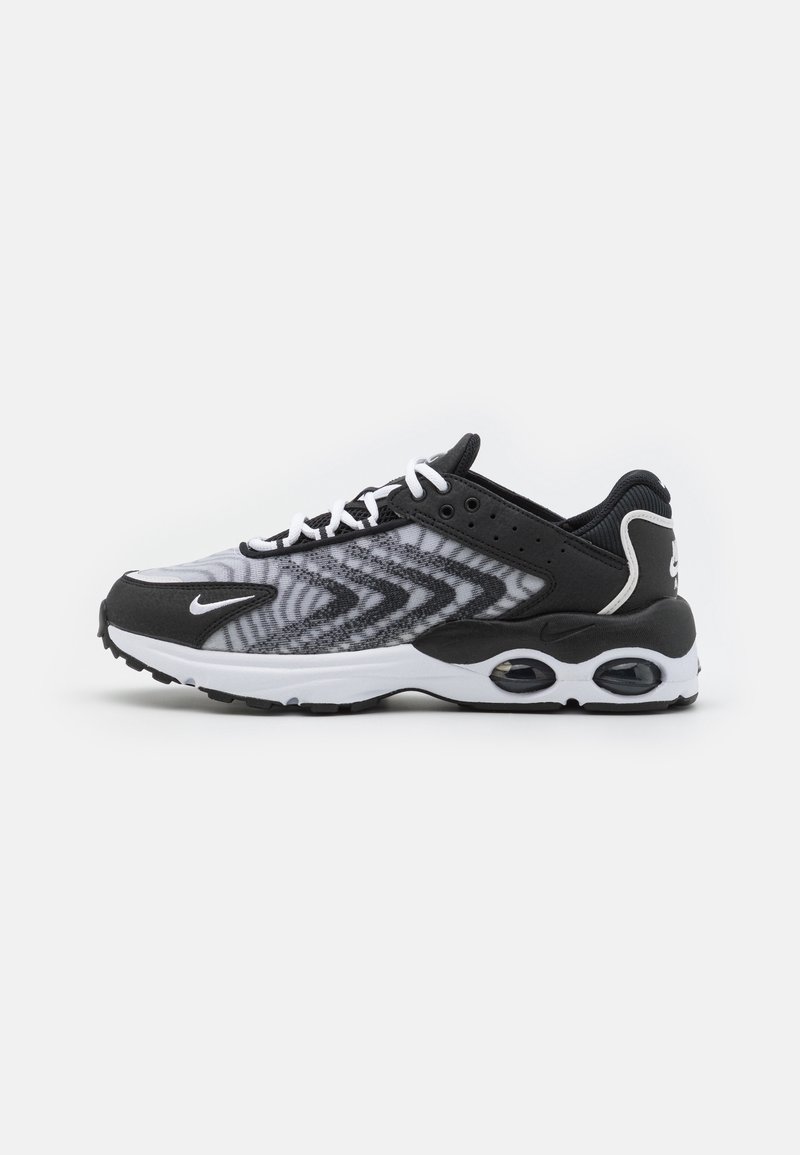 Black and white athletic shoe featuring a mesh upper with chevron patterns, rubber sole, and laces for secure fit. Air cushioning visible.