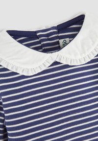 Blau-weiße gestreifte Bluse mit einem weißen Rüschenkragen. Weicher Stoff mit einem klassischen, runden Ausschnitt und einem sichtbaren Etikett auf der Rückseite.