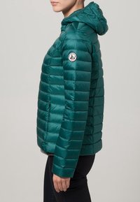 Turkusowa kurtka puchowa z kapturem, z pikowanymi panelami, bocznymi kieszeniami oraz naszywką z logo na lewym ramieniu. Gładka, błyszcząca tekstura.