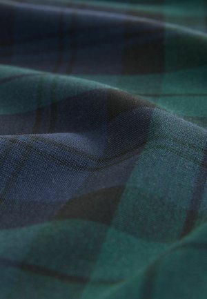 Tartanstoff mit grünen und marineblauen Karomustern, mit einer weichen, strukturierten Oberfläche, die komplexe gewebte Details zeigt.