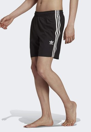 Shorts deportivos negros hechos de un tejido ligero. Presentan acentos en tres franjas blancas en los lados y una cinturilla elástica.