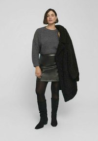 Czarna mini spódnica z sztucznej skóry, szary sweter z dzianiny i czarny oversize'owy płaszcz. Noszone z czarnymi zamszowymi kozakami do kolan. Gładkie i teksturowane materiały.