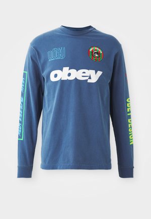 Blaues Langarm-T-Shirt aus Baumwolle. Auf der Vorderseite befindet sich großer, weißer "obey"-Schriftzug, ein grafisches Emblem auf der linken Brust und bunte Schriftzüge auf den Ärmeln.