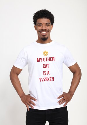Hvid bomulds T-shirt med et gult grafisk motiv og røde bogstaver: "MIN ANDEN KAT ER EN FLERKEN." Korte ærmer og rund halsudskæring.