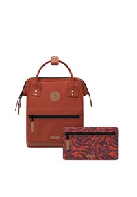 Red fabric backpack with a top handle, zip front pocket, and leather logo. Accompanied by a matching wallet featuring a leaf pattern.