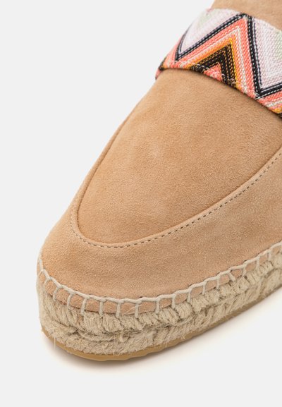 Brūni zamša slip-on kurpes ar austu rakstu siksnu rozā, melnā un oranžā krāsā. Aprīkotas ar jutu virves zoli un noapaļotu purngalu.