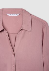 Blusa rosa chiaro, con colletto e chiusura a bottoni, presenta una texture di tessuto liscia e un design semplice, etichettata "Terranova" taglia S.