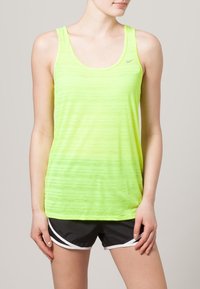 Neonowożółty sportowy tank top bez rękawów z poziomymi, teksturowanymi paskami; małe szare logo na piersi; zestawiony z czarnymi szortami.