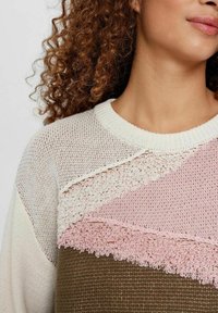 Pletena majica sa bijelim, ružičastim i smeškim teksturiranim panelima. Ima okrugli izrez i složene detalje na prednjem delu.