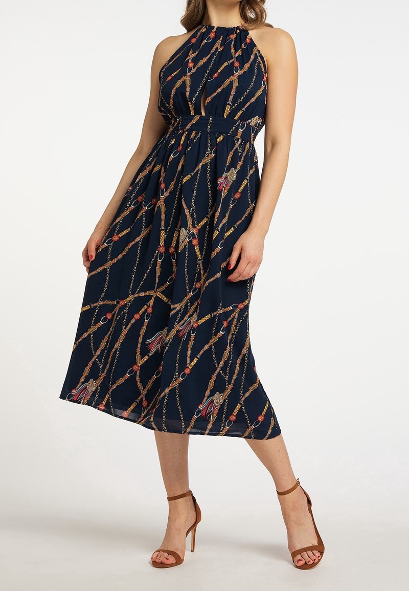 Marinblå halterklänning med figursydd bodice, flödande kjol och guldkedjemönster, prydd med röda och blå accenter samt en strukturerad tyg.