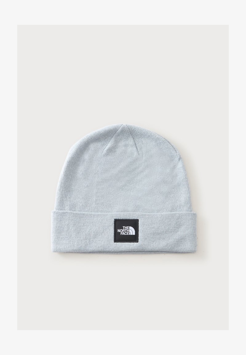 Bonnet tricoté gris clair avec revers plié présentant un patch carré noir avec le logo The North Face en texte blanc.