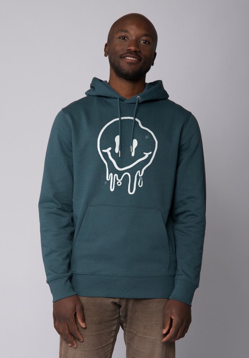 Teal hoodie met een groot wit druppelend smiley-gezicht graphics, trekkoordcapuchon, voorzak en ribgebreide zoom en boorden.