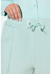 Jasnoniebieskie, miękkie spodnie dresowe z elastycznym pasem, sznurkiem do regulacji i bocznymi kieszeniami, charakteryzujące się luźnym krojem.