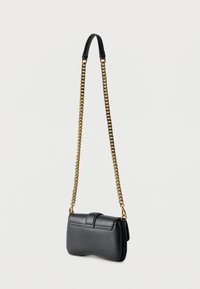 Μαύρο δερμάτινο τσαντάκι ώμου με λουρί αλυσίδα σε χρυσό χρώμα και μαύρο δερμάτινο μαξιλαράκι ώμου, απεικονίζεται κρεμασμένο πάνω σε λευκό φόντο.