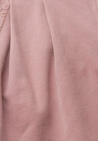 Gros plan sur un tissu rose doux avec un motif sergé diagonal et des plis subtils.