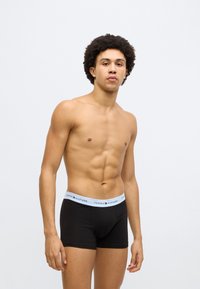 Mustad bokserid sinise elastse vöökohaga, millel on "Tommy Hilfiger" logo, vormivad ja siledast puuvillast.