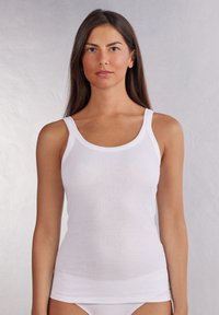 Witte geribde tanktop met brede bandjes, zachte textuur en een aansluitend ontwerp. Het heeft een ronde halslijn en een rechte zoom.