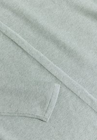 Světle šedý svetr s strukturovaným pletením, žebrovanými manžetami a hladkým zakončením okrajů. Jednoduchý a minimalistický design.