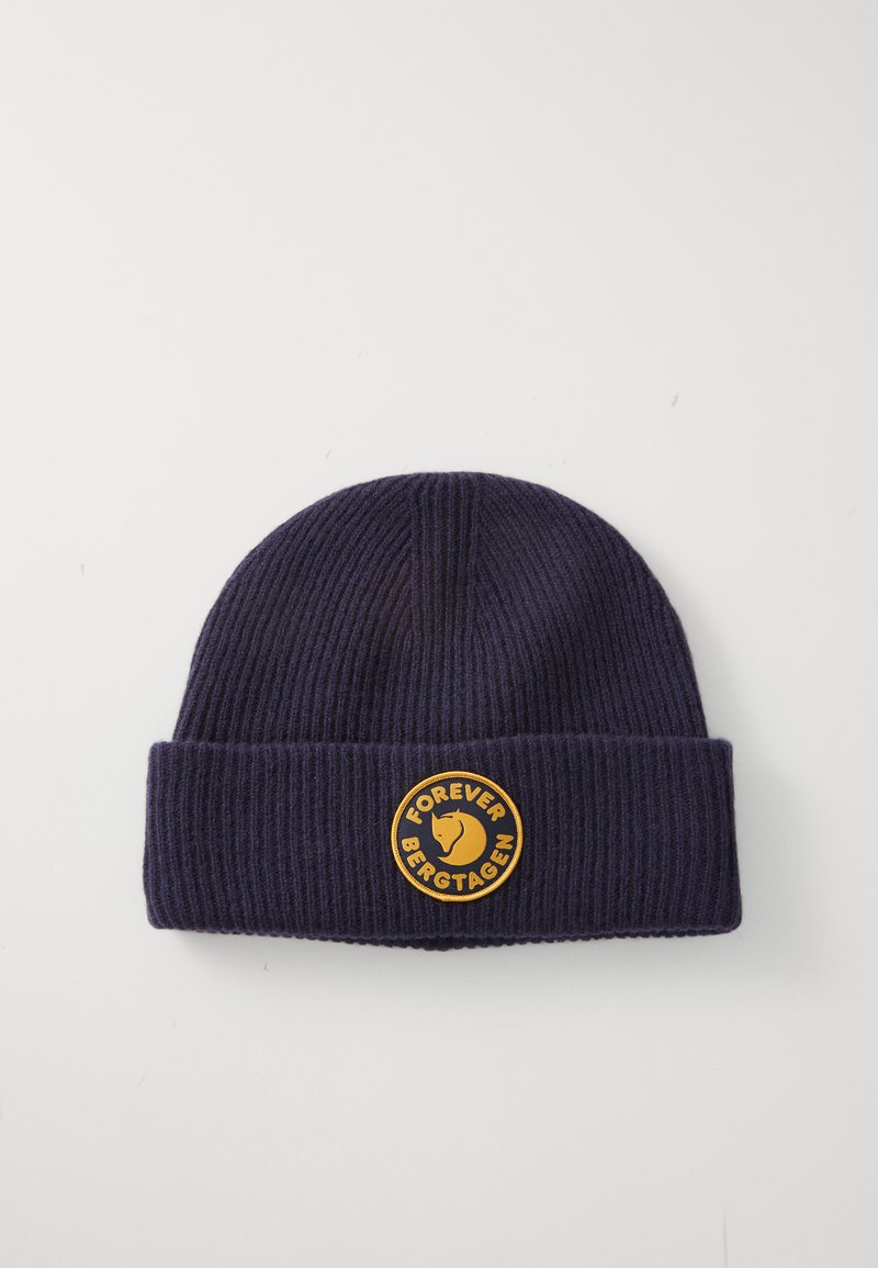 Knitted dark navy beanie with a folded cuff, featuring a circular yellow patch with "FOREVER BERGTAGEN" and a stylized animal logo.
