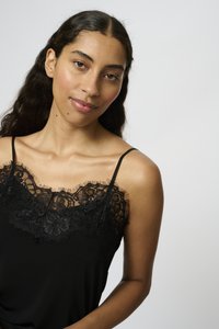 Camisola nera con pizzo lungo il collo e motivi floreali. Spalline sottili e tessuto morbido e liscio.