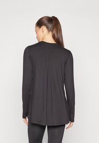 Black long-sleeve top with a round neckline, featuring a pleat detail at the back and a slightly curved hem. Smooth, stretchy fabric.