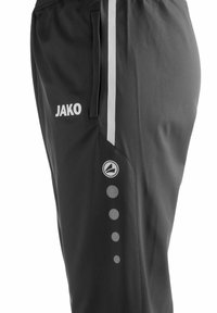 Schwarze Sporthose mit weißem Logo, Seitentasche, reflektierenden Streifen und kreisförmigen Akzenten, die vertikal an einem Bein angeordnet sind.