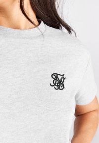 Grå bomulds t-shirt med korte ærmer og rund hals, med et sort broderet logo på venstre bryst.