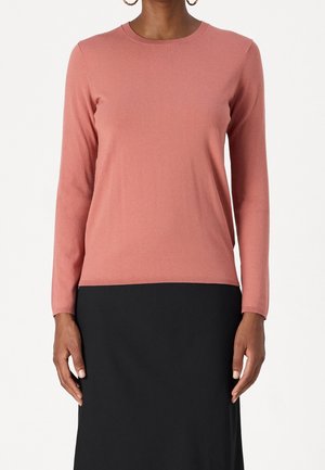Rosa langärmliger Strickpullover mit Rundhalsausschnitt, glatter Textur und figurbetontem Design, kombiniert mit einem schwarzen Rock. Schlichter, minimalistischer Stil.