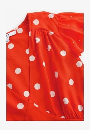 Sarkans kleitas ar īsām pūkainām piedurknēm, kas izdaiļota ar lieliem baltiem punktiņiem. Izgatavota no viegla auduma ar vieglu mirdzumu un ruļļu detaļām.