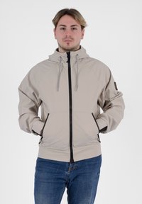 Giacca beige con cappuccio, zip nera, tasche laterali e cordini regolabili. Realizzata in materiale morbido e leggero con una texture liscia.