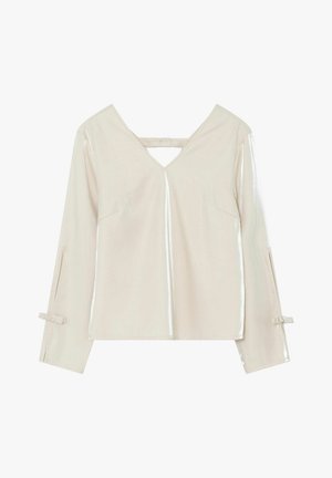 Bílá blůza s dlouhými rukávy a výstřihem do V, detaily na zadním popruhu, mírně lesklá látka a malé mašle na manžetách rukávů na jednobarevném pozadí.