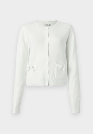 Cardigan alb, tricotat, cu mâneci lungi, decolteu rotund, închidere cu nasturi și două buzunare decorate cu fundițe mici. Material moale și texturat.