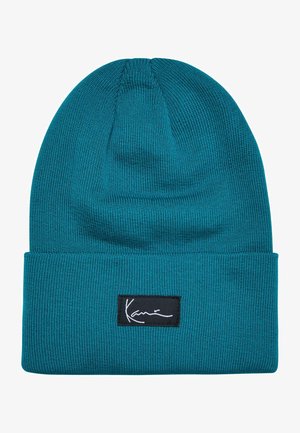 Türkiser Strickmütze mit umgeschlagenem Bund. Hat ein schwarzes rechteckiges Etikett mit weißem Signaturstich. Weicher Stoff, dehnbares Material.