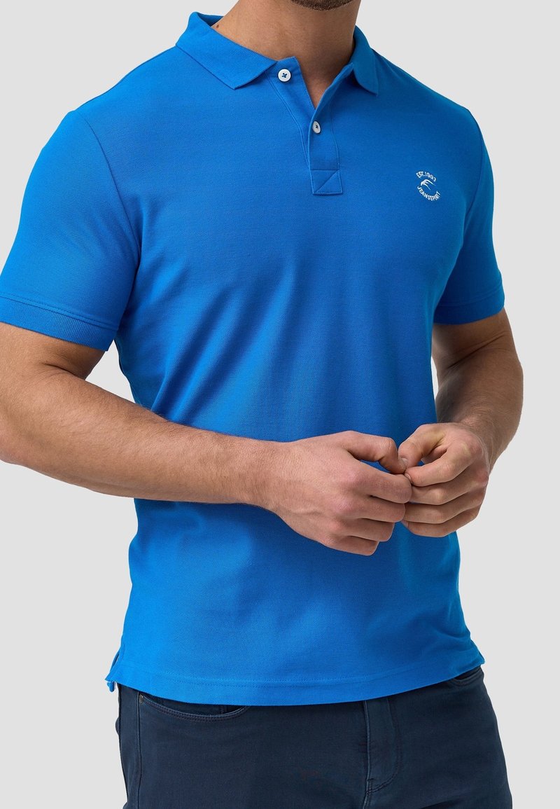 Polo bleu en coton lisse avec col, patte de boutonnage à deux boutons et petit logo sur la poitrine. Manches courtes, design ajusté.