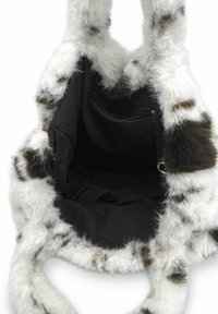 Sac fourre-tout en fausse fourrure présentant un motif tacheté blanc et marron, intérieur en tissu noir, grande ouverture, et poignées doubles pour le porter.