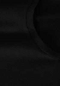 Schwarzer Stoff mit glatter Textur, runder Ausschnitt und minimalen Nähten, zeigt einen subtilen Glanz, der für synthetische Materialien typisch ist.