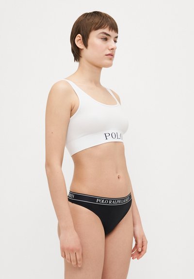 Balti ribotas braletas su tamsiai mėlynu "POLO" diržu, derinamas su juodais kelnaitėmis su baltu "POLO RALPH LAUREN" diržu. Lygus audinio paviršius.