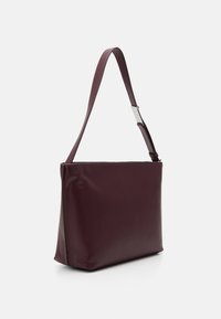 Burgundy shoulder bag with a smooth, glossy finish. Features a long adjustable strap and a minimalist rectangular shape. Silver hardware accent.