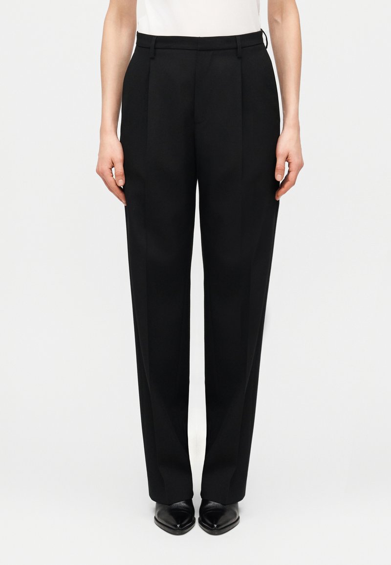 Pantalon noir sur mesure à taille haute, avec plis à l'avant et coupe droite. Texture lisse et style minimaliste.