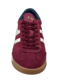Baskets en suède bordeaux avec rayures blanches, bout rond et semelle en caoutchouc marron. Logo doré sur la languette, lacets passant par des œillets renforcés.