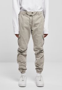 Helle beige Cargo-Hosen mit elastischem Bund und gerafften Bündchen. Verfügt über mehrere Seitentaschen und eine glatte, strapazierfähige Stoffstruktur.