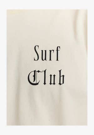T-shirt in cotone di colore crema con una scritta nera che recita "Surf Club" in un font dallo stile vintage.
