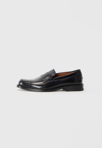 Black leather loafer with a rounded toe, raised stitching detail on the vamp, and a low stacked heel. Smooth texture and formal design.