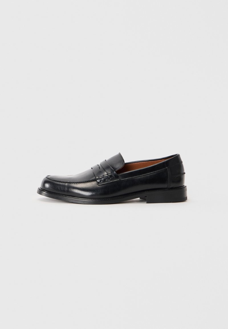 Black leather loafer with a rounded toe, raised stitching detail on the vamp, and a low stacked heel. Smooth texture and formal design.