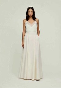 Fehér ruha csipkés, díszített felsőrésszel és laza, redőzött maxi szoknyával. Állítható pántokkal és oldalzsebekkel rendelkezik.