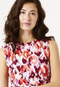 Mouwloze top met bloemenpatroon en ribbeltextuur in tinten rood, roze en wit. Strak model met een ronde halslijn.