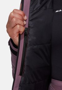 Innenansicht einer lila Puffjacke mit glattem schwarzen Futter und Reißverschlussdetails. Der Stoff hat eine glänzende Textur und zeigt eine Nahaufnahme des Reißverschlusses.