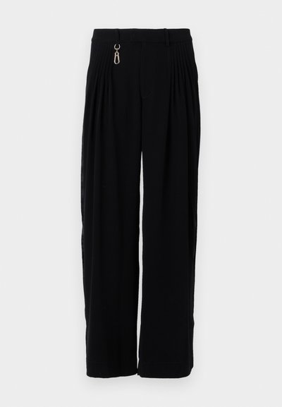 Fekete, bő szárú nadrág plisszékkel, cipzárral, övhurkokkal és sima szövet textúrával. Nincsenek látható minták vagy fémrészek.