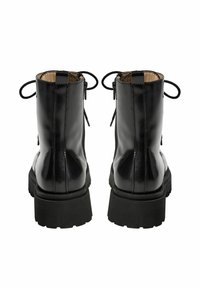 Melnas lakotas ādas potītes zābaki ar strukturētu, blīvu gumijas zoli; ir apaļa purngala forma, vilkšanas cilpas un šņorēšanas akcenti.