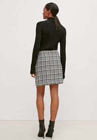 Black ribbed turtleneck paired with a gray and white checkered skirt, featuring a fitted silhouette and black ankle boots.